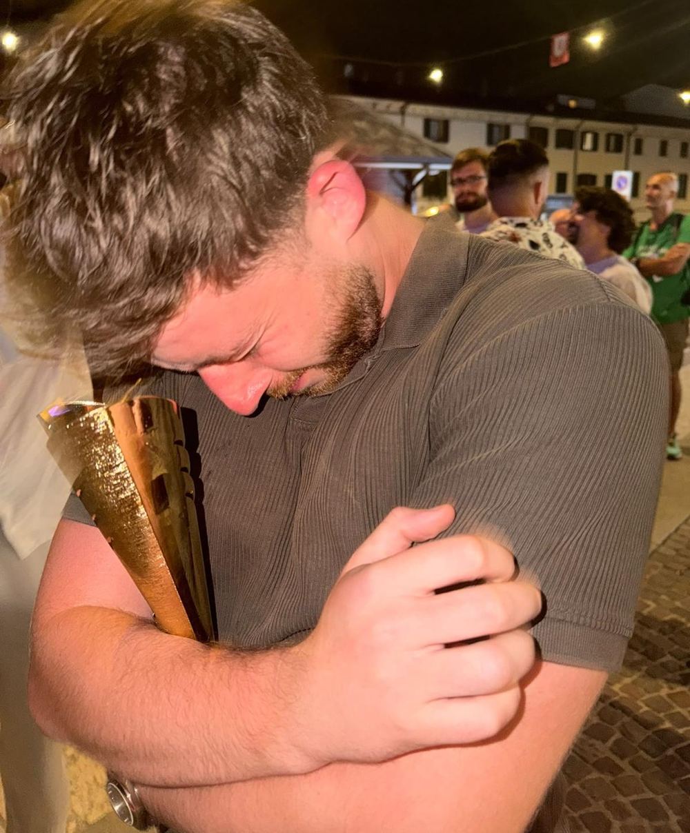 A player hugging a gold trophy tightly to his chest at night